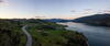 Panoramic view of road, hills, and lake between Kelowna and Vernon at dusk